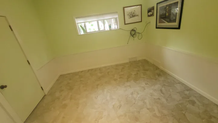 Alternate room view showing the stone floor, painted walls, white trim, and doorway.