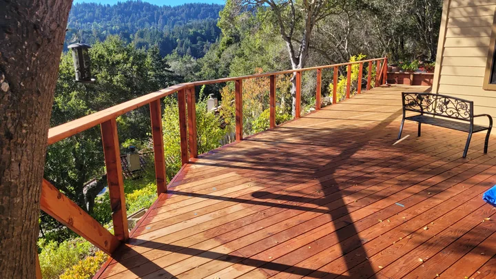 Deck and wood railing frame during staining, with open spaces between the posts before cable installation.