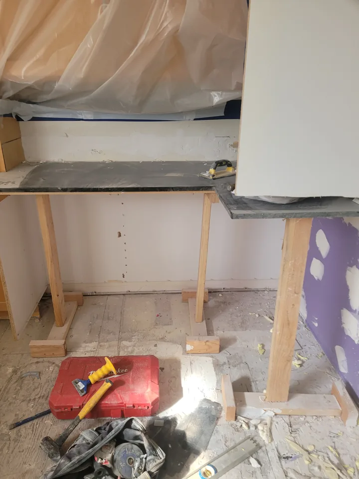 Granite countertop held on temporary wood supports while the cabinetry beneath is open for repairs.
