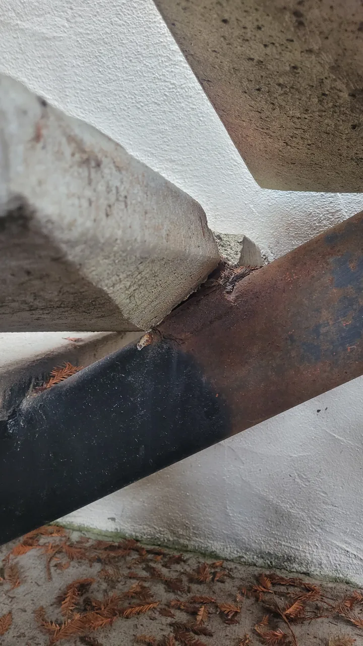 Close-up of the rusting tread bracket and deteriorated edge before the repair.