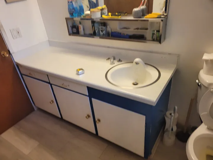 Original white sink assembly and countertop on a blue-and-white bathroom vanity.